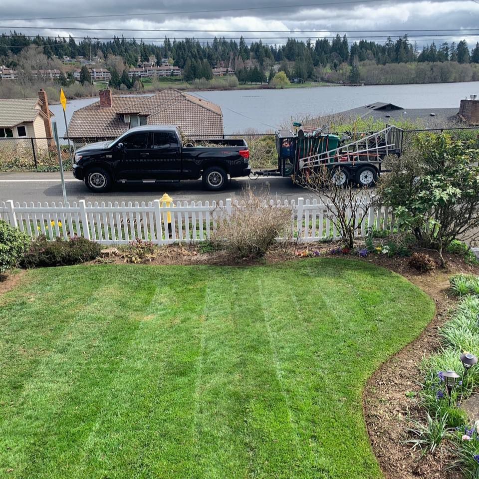 Striped lawn with the company truck and trailer parked by a lake view